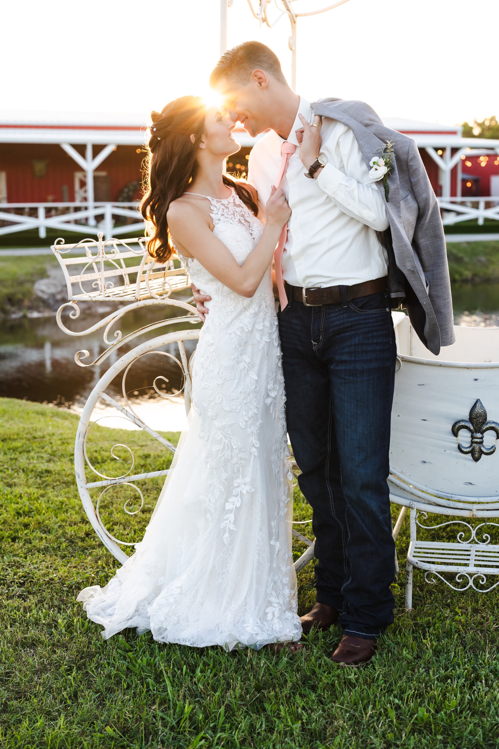 Newlyweds smiling together at sunset beside a decorative carriage